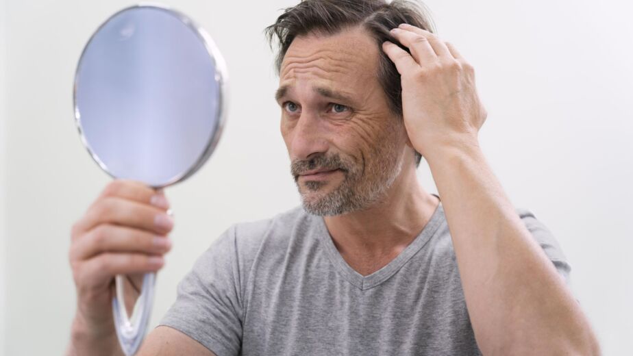 Man examining his hair loss in a mirror